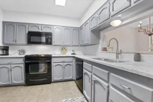 CollegetownにあるBaton Rouge condo near LSUの白いキャビネットと黒の電化製品が備わるキッチン