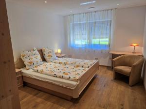 a bedroom with a bed and a chair and a window at Ferienwohnung am Eichberg in Winkl bei Grabenstätt