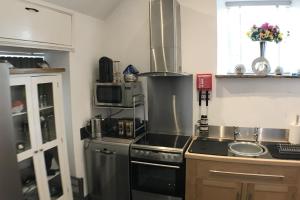 a kitchen with a stove and a sink and a microwave at Charming 1 Bed Peak Dist Cottage Barn Alton Towers in Whiston
