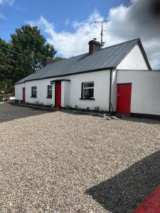 BlackwatertownCampbell's Cottage的一栋白色建筑，红色大门，位于一条碎石车道上