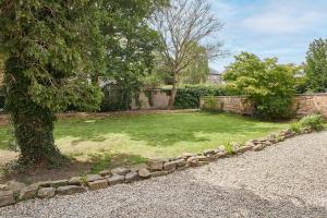 a garden with a tree and a stone wall at Host & Stay - Thorneville House in Knaresborough