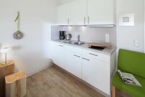 una cocina con armarios blancos y una silla verde en Sonnengruß, en Juist
