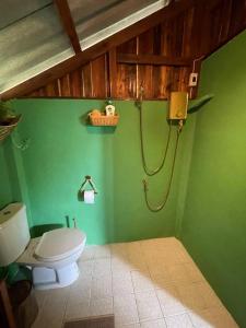 a bathroom with a toilet and a green wall at Forest Retreat House Hammock & Private Terrace in Ban Nok