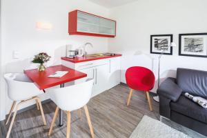 a living room with a red table and a couch at Appartementhaus Bracht - Kleine Welle in Juist +7 photos