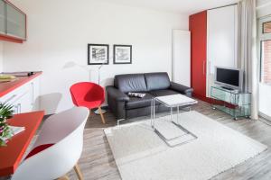 a living room with a black leather couch and a table at Appartementhaus Bracht - Kleine Welle in Juist