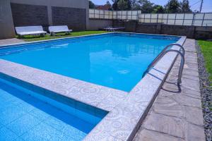 a swimming pool with a stairway leading into the water at 1BR Luxury Apartment Milimani Nakuru, Empiris with Pool, Gym, Near Golf Club in Nakuru