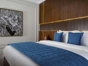 a hotel room with a large bed with blue pillows at Mercure Tashkent South in Tashkent +89 photos