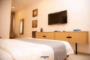 a bedroom with a bed and a flat screen tv at Amani inn hotel in Kinshasa