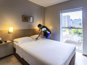 Una mujer está haciendo una cama en una habitación de hotel. en ibis Styles Belém do Pará, en Belém