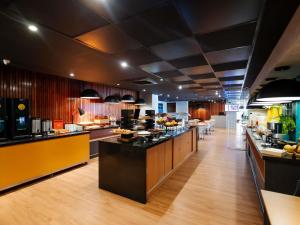 a large kitchen with a long counter with food on it at Ibis Styles Belém Hangar in Belém