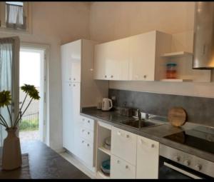 a kitchen with white cabinets and a sink at Casa Azzurra in Malcesine