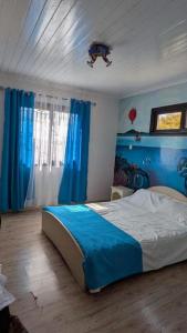 a bedroom with a large bed with blue curtains at Résidence Hay Guest House in Antananarivo