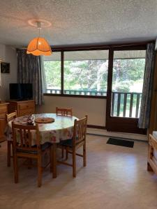Un comedor con mesa y sillas y una gran ventana. en Loue appartement au Mont Dore AUVERGNE, en Le Mont-Dore