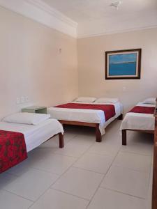 a room with three beds and a picture on the wall at Hotel Pousada Acácia da Barra in Salvador