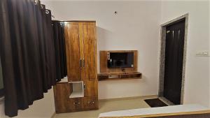 a living room with a tv and a wooden cabinet at Balaji Lodging in Pandharpur