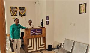 two men standing behind a podium in a room at Balaji Lodging in Pandharpur