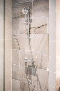 a shower with a shower head in a bathroom at Modern 1BR Condo w Balcony Near Central Phuket in Ban Na Khua