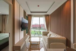 a living room with a couch and a tv at Modern 1BR Condo w Balcony Near Central Phuket in Ban Na Khua
