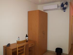 a room with a desk and a cabinet and a fan at Rivotorto Retreat House in Birkirkara