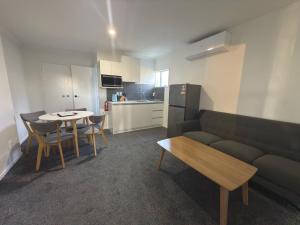a living room with a couch and a table and a kitchen at Saints Apartment Junior Suite in Taupo