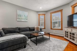 een woonkamer met een bank en een tv bij Tufts 2 Bed & Office - Free Parking in Medford