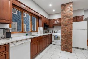 una cocina con armarios de madera y una pared de ladrillo en Tufts 2 Bed & Office - Free Parking, en Medford