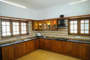 a large kitchen with wooden cabinets and a sink at Kanattu Homestay in Muttam