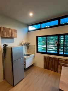 een keuken met een koelkast en twee grote ramen bij The Wild Villa Phuket Rawai in Nai Harn Beach