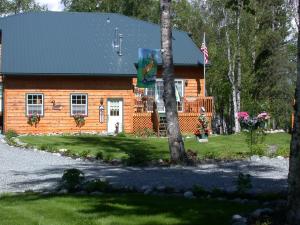 a log cabin with an american flag in front of it at Alaska's Lake Lucille Bed & Breakfast in Wasilla