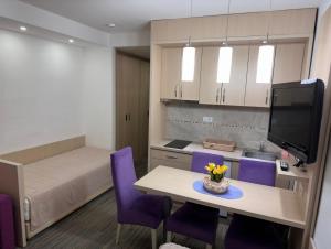a room with a kitchen and a table with purple chairs at Angela 103 in Kopaonik