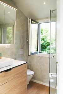 a bathroom with a sink and a toilet and a window at Familienfreundliches Designer Ferienhaus im Grünen an der Grenze zu Österreich I 5 Personen in Untergriesbach