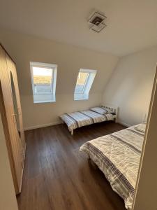 a bedroom with two beds and two windows at Erics Gästehaus in Uetersen