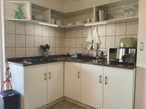 een keuken met witte kasten en een spoelbak bij Pebbles & Shells in Kleinmond +9 foto's