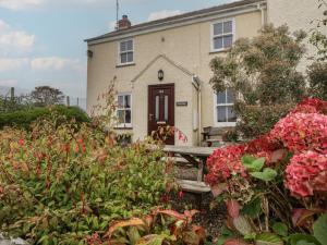 une maison avec un banc et des fleurs devant elle dans l'établissement Garth Cottage, à Saint David's