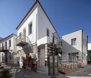 a white building with a balcony and tables on a street at L Anima in Skiathos