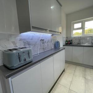 eine Küche mit weißen Schränken und einem Toaster auf der Theke in der Unterkunft 4 Bedroom Terraced House with Huge Garden in Pinner