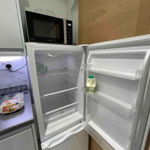 ein offener Kühlschrank mit einer Mikrowelle darauf in der Unterkunft 4 Bedroom Terraced House with Huge Garden in Pinner + 20 Fotos