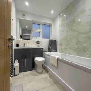 ein Badezimmer mit Badewanne, Toilette und Dusche in der Unterkunft 4 Bedroom Terraced House with Huge Garden in Pinner