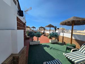 eine Terrasse mit Stühlen und Sonnenschirmen an einem Gebäude in der Unterkunft Hostal Nerjasol in Nerja