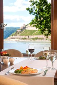a table with a plate of food and wine glasses at NH Bingen in Bingen am Rhein