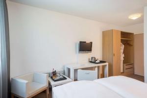 a bedroom with a bed and a desk and a tv at NH Bingen in Bingen am Rhein +17 photos