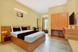 a bedroom with a large bed and a television at Hotel O MYSORE CASTLE in Belagula +21 photos