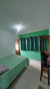 a green bedroom with a bed and a chair at Casa Hostel da Cida in Pipa