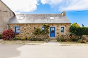 uma pequena casa de tijolos com uma porta azul em Charmante maison au cœur d'Hengoat em Hengoat