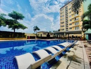 a swimming pool with lounge chairs next to a building at Miyu's Staycation Place in Biñan