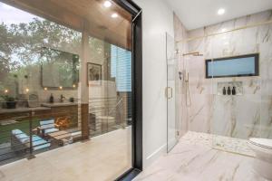 a bathroom with a shower and a toilet and a television at The ATX South Lamar Creekside Retreat with a pool in Austin