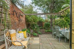 un patio con una mesa y sillas y una pared de ladrillo en Cosy City-Centre House near Train Station & Business School, with Garden, en Oxford