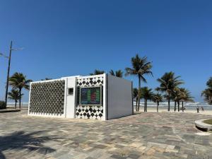 a building on the beach with palm trees in the background at Apto vista Mar c/ vaga a 200m da Praia da Mirim! in Praia Grande