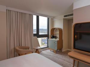 ゴスフォードにあるvoco Gosford by IHGのベッドと大きな窓があるホテルの部屋