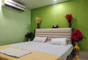 a bedroom with a bed with green walls and flowers at RD Residency Hotel at IIT Gate Kanpur in Kānpur